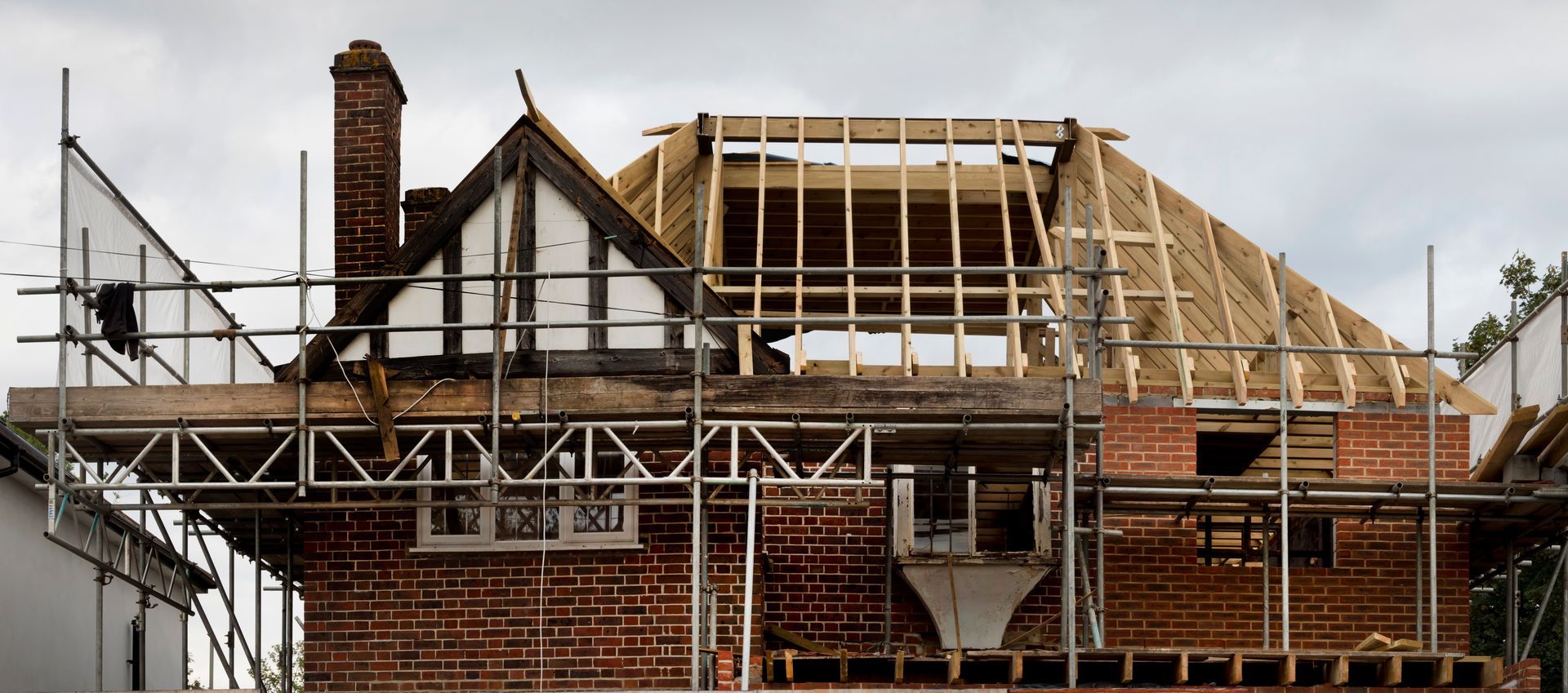 House under renovation with scaffolding and a partially re-roofed roof