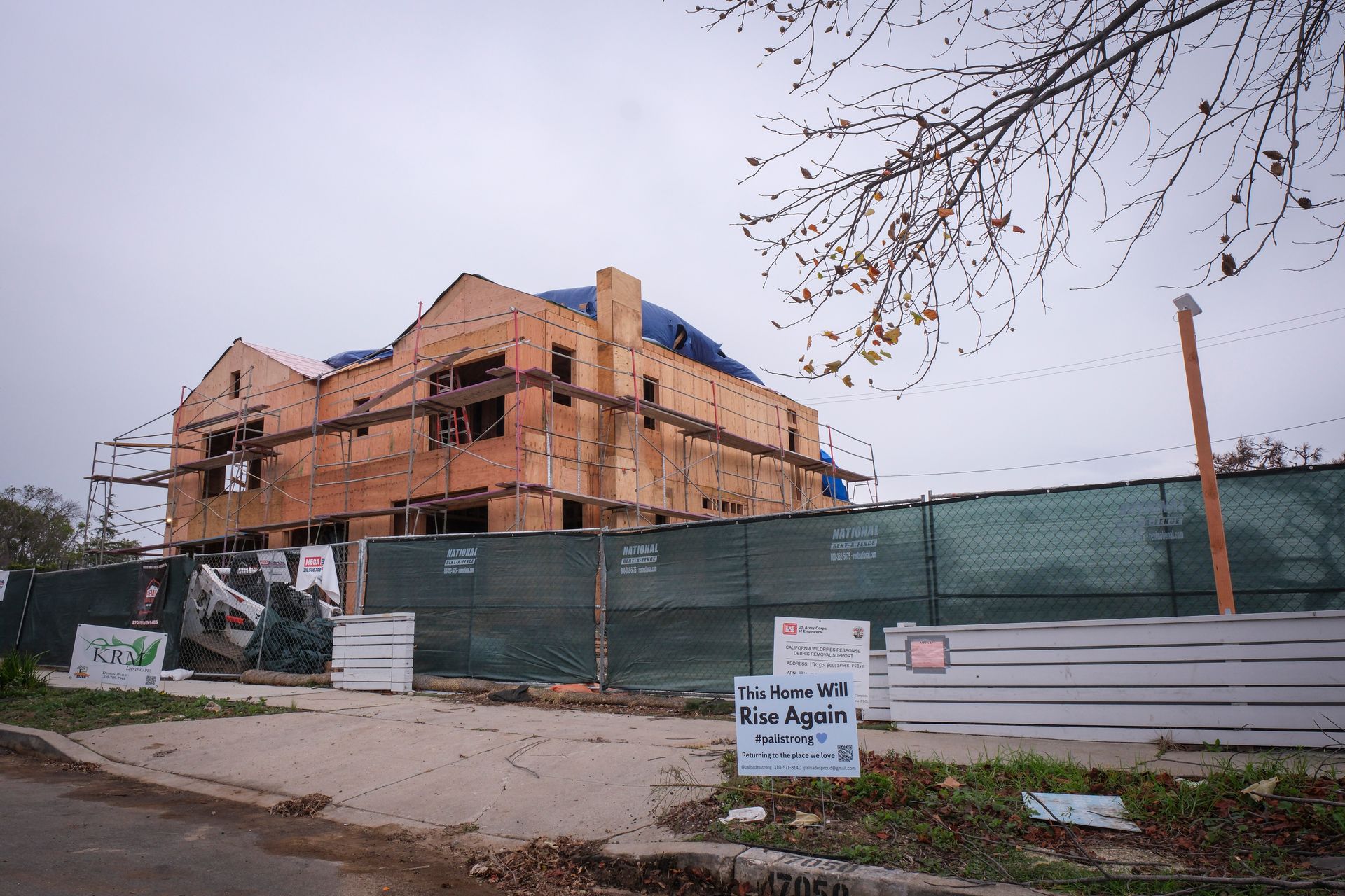 Partially built house behind green construction fencing on a roadside corner