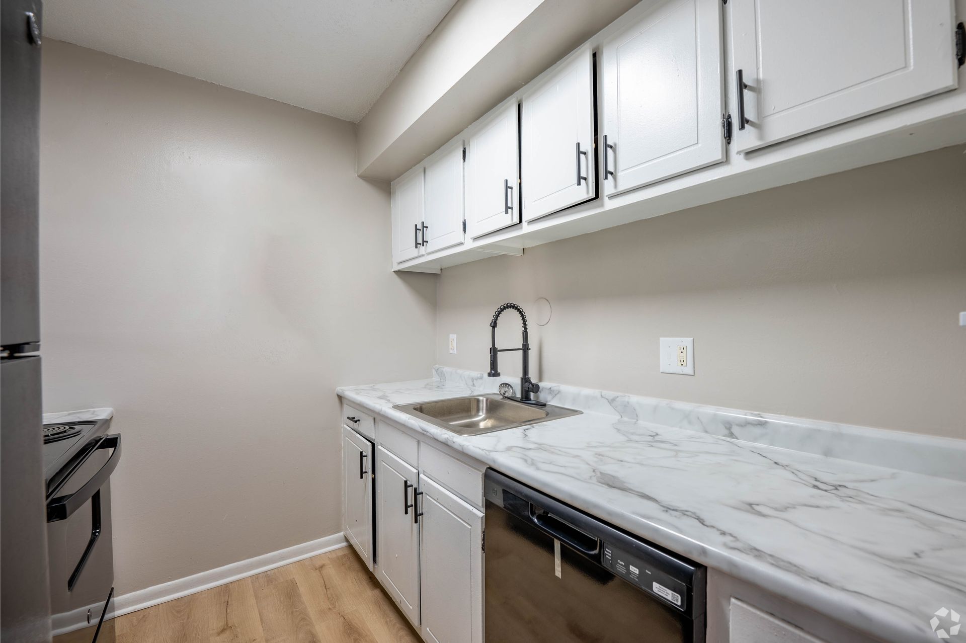 Kitchen with white cabinets, marble countertops, and black faucet.