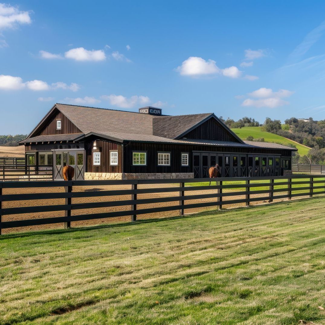 A horse is standing in front of a barn with a fence around it.