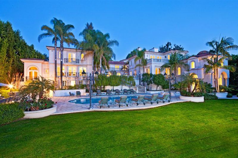 A large house with a pool and palm trees in front of it