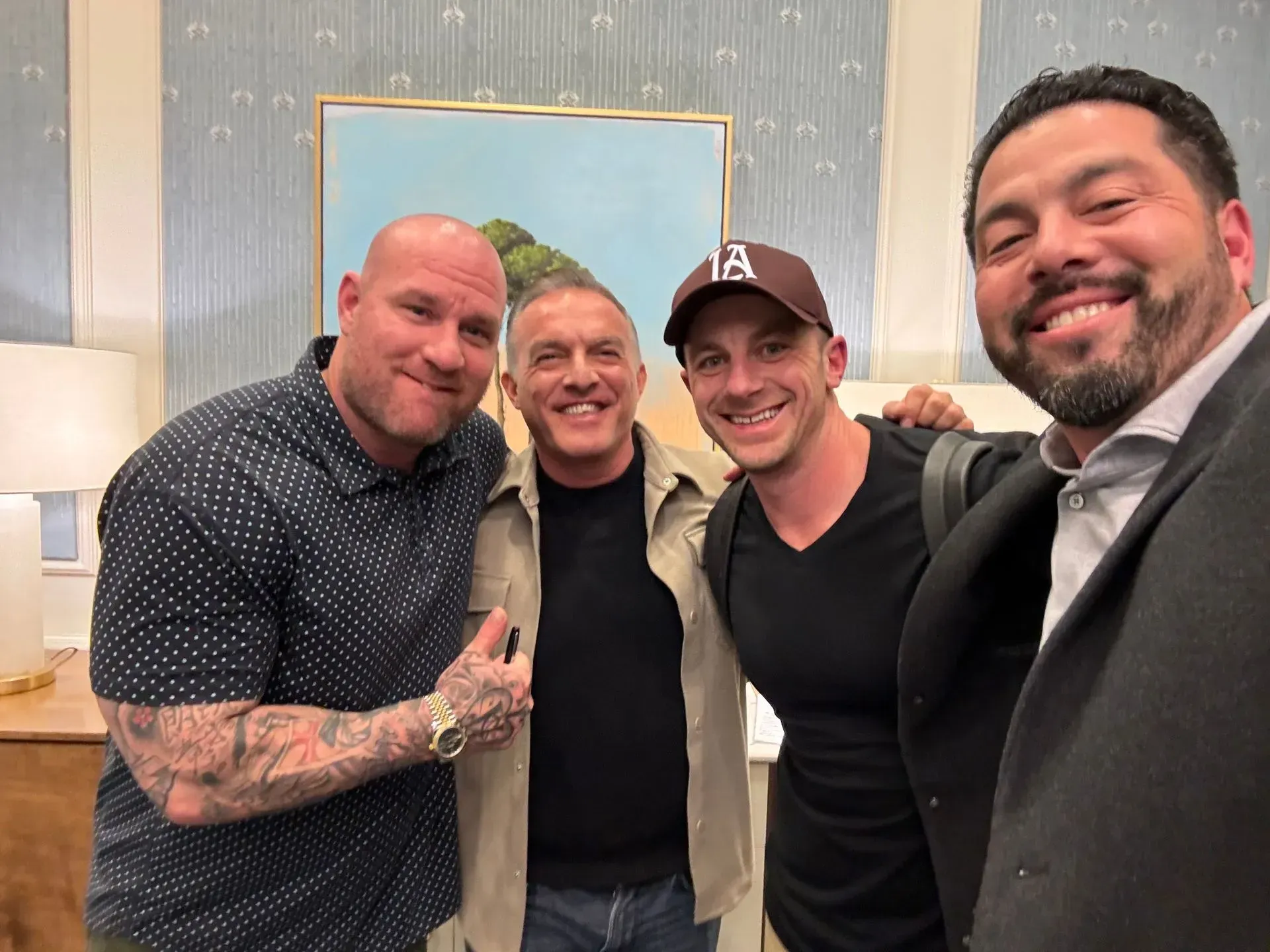 A group of men posing for a picture with one wearing a la hat