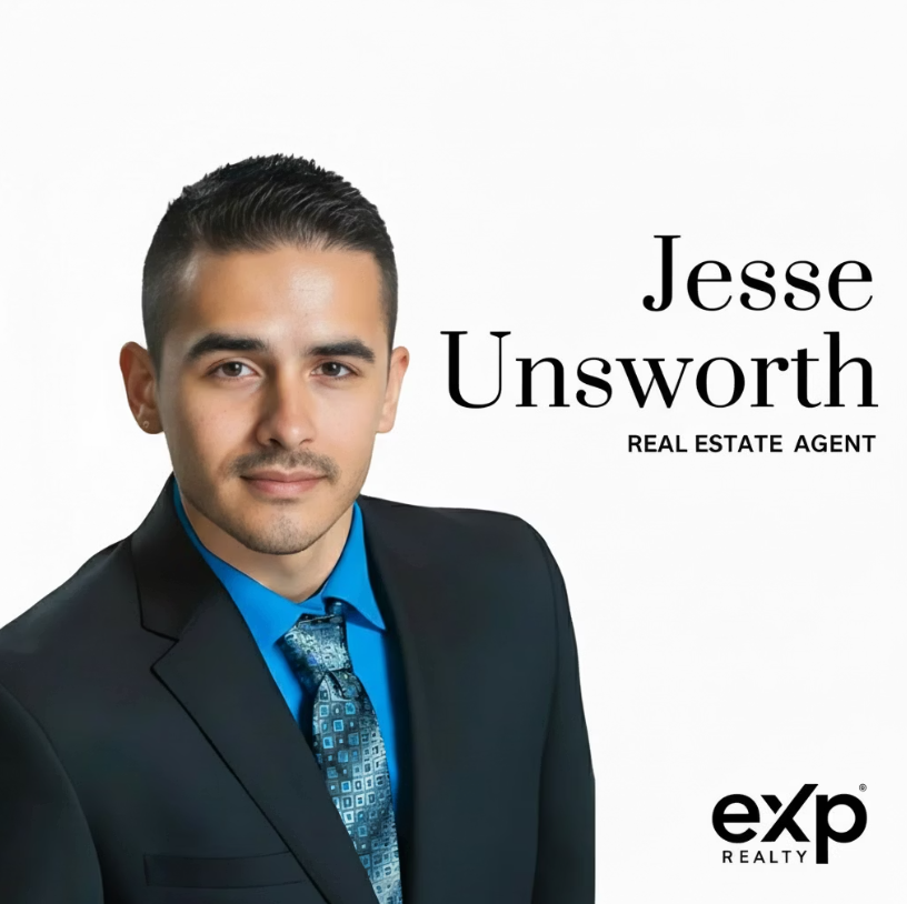 Portrait of Jesse Unsworth, real estate agent, in a dark suit with blue tie on a white background.