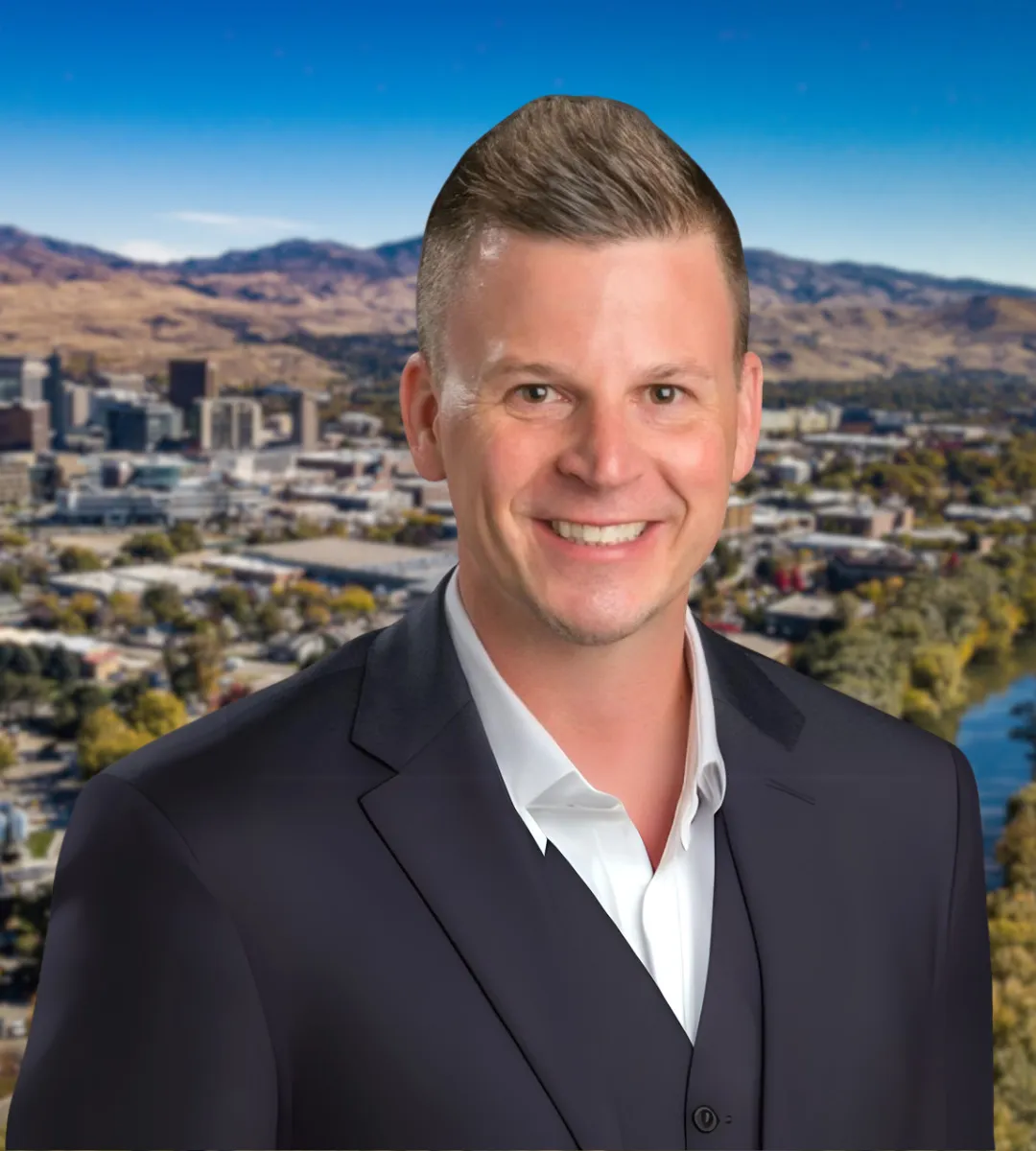 Smiling man in a navy suit with a cityscape and mountains in the background