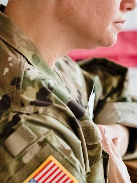 A woman in a military uniform has an american flag patch on her shoulder