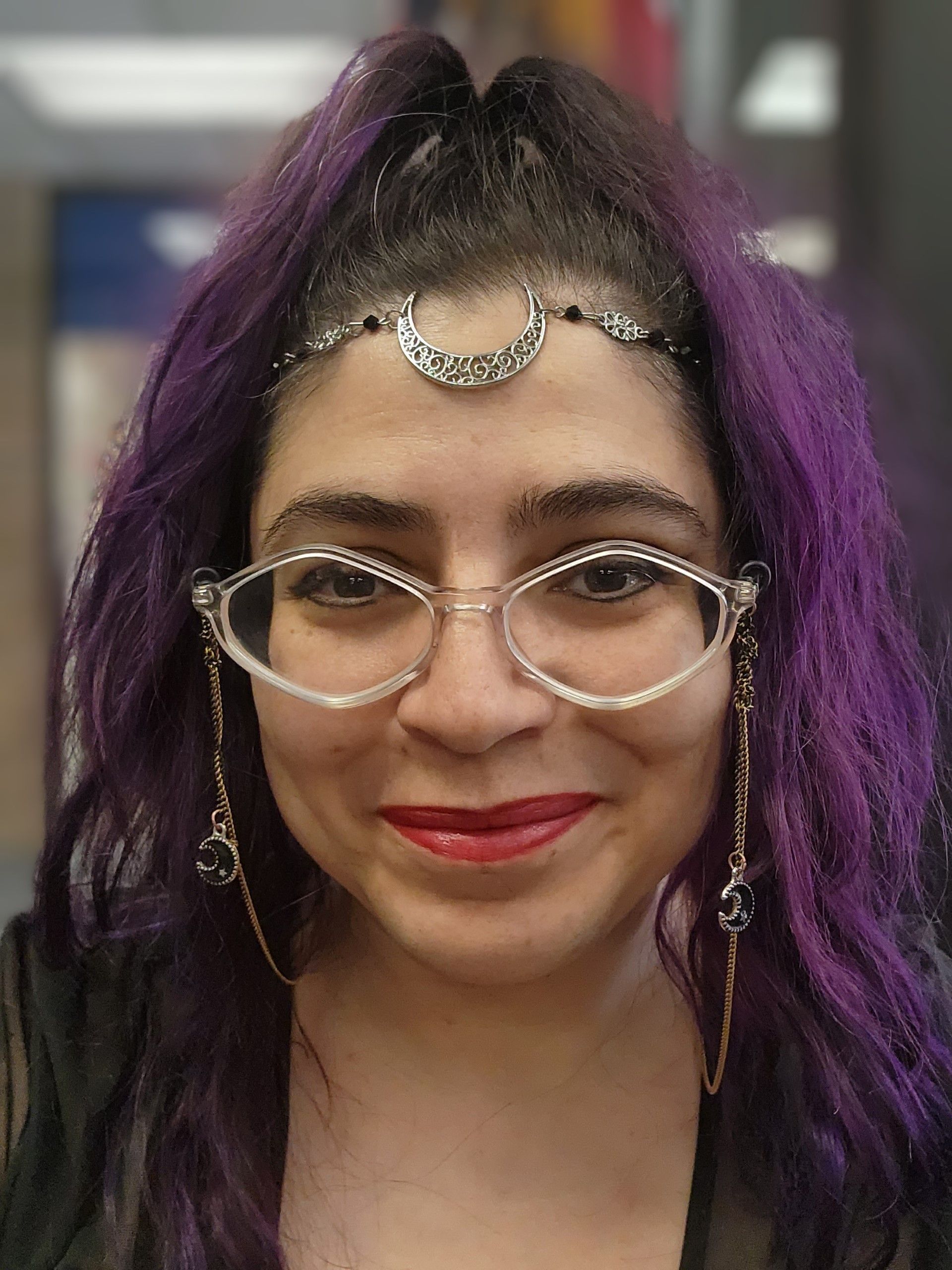 A woman with purple hair and glasses is smiling for the camera, Aedis Lavaeu