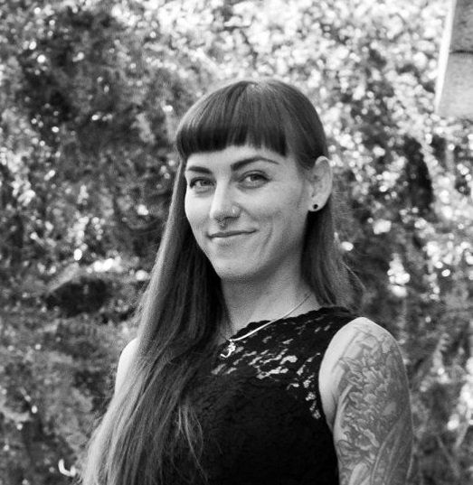 A black and white photo of a woman with long hair and a tattoo on her arm, Camille.