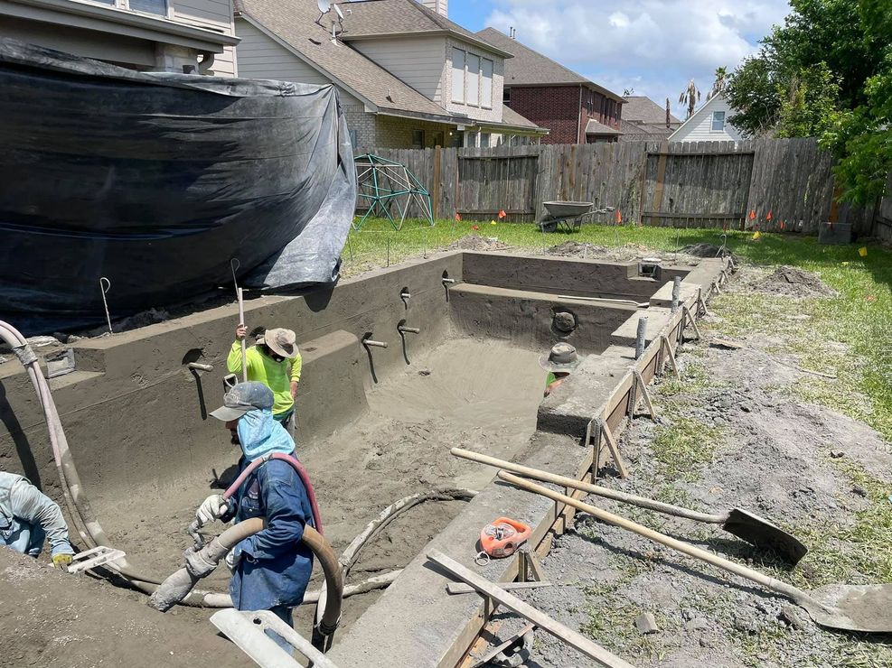 A group of construction workers are working on a swimming pool.