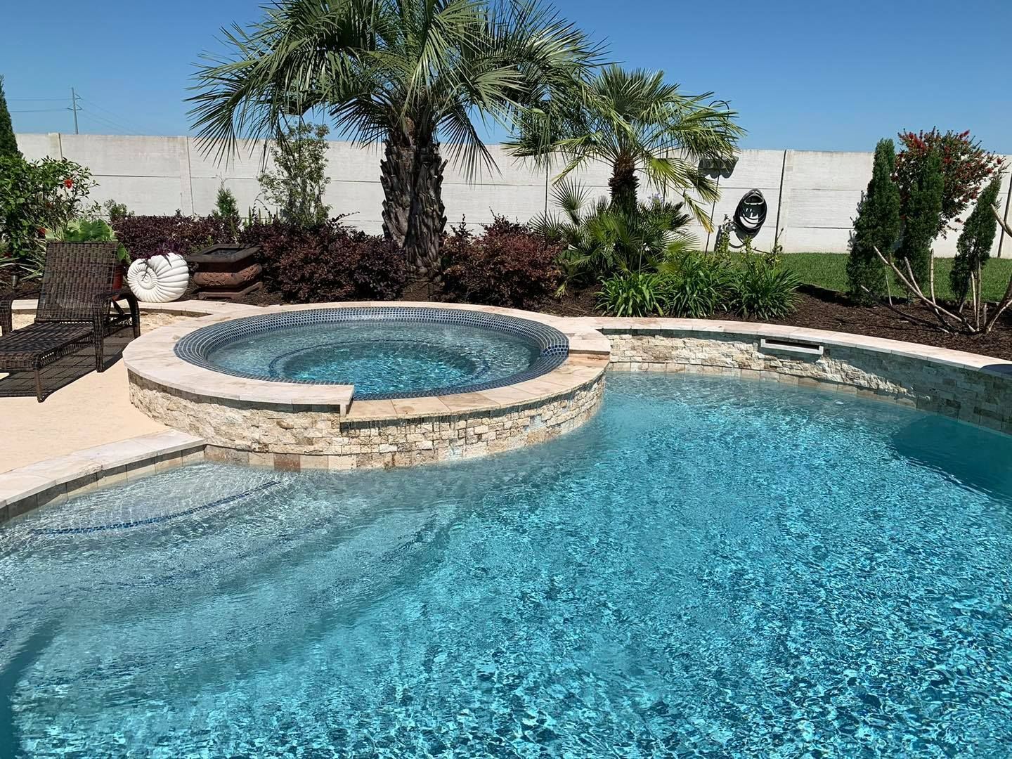 A large swimming pool with a hot tub in the middle surrounded by palm trees.