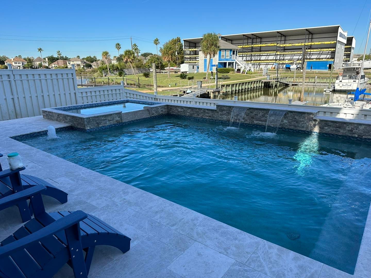 A large swimming pool is surrounded by chairs and a fence.