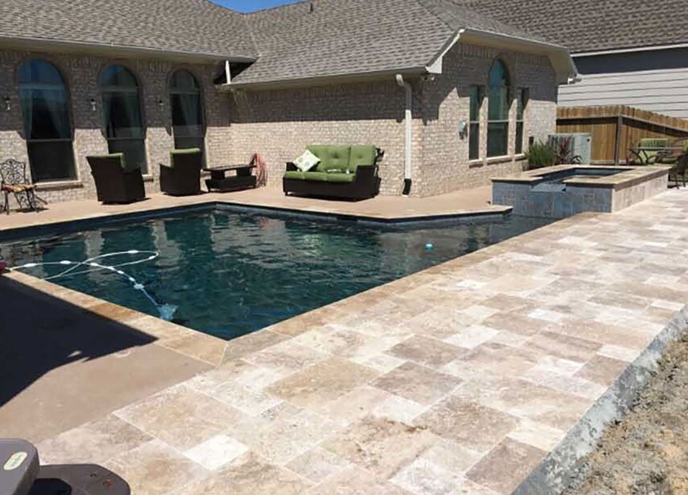 There is a large swimming pool in the backyard of a house.