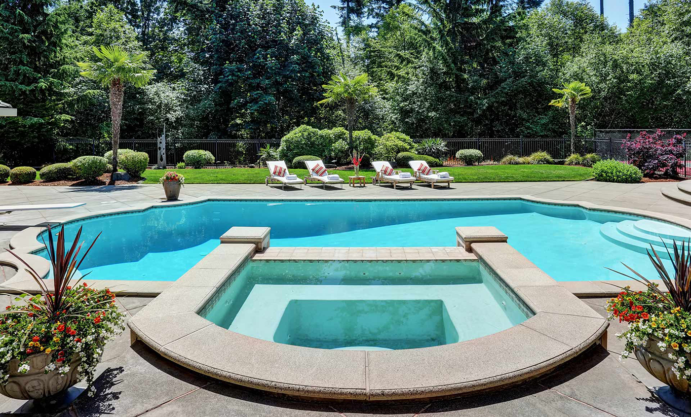 A large swimming pool with a hot tub in the middle of it.