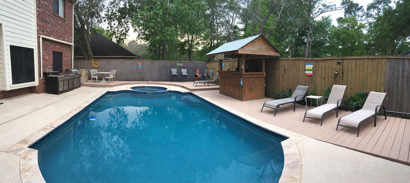 There is a large swimming pool in the backyard of a house.
