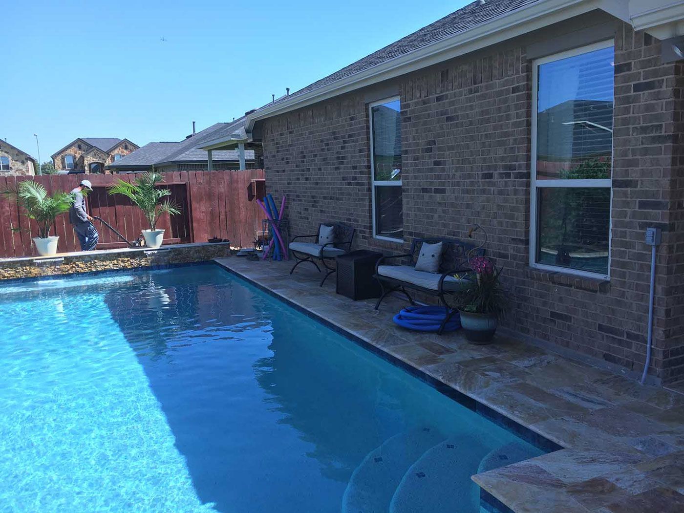 A brick house with a large swimming pool in front of it.