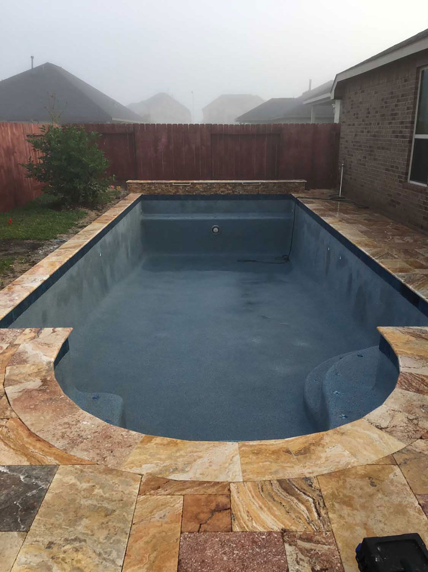 A large swimming pool is sitting in the backyard of a house.