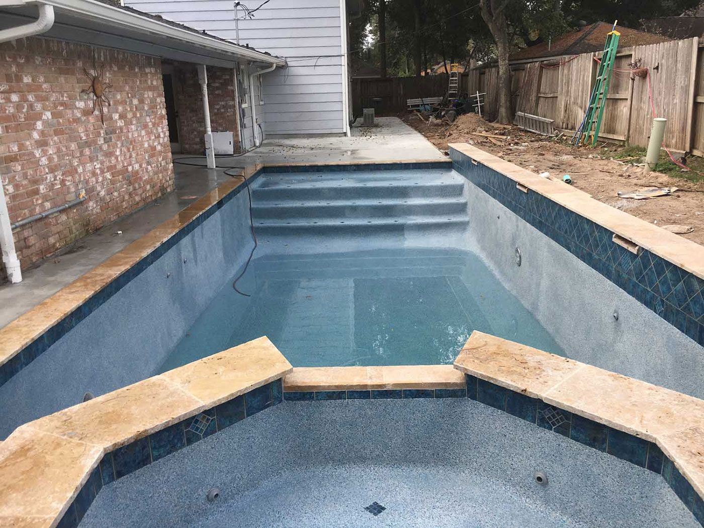 A large swimming pool is being built in the backyard of a house.