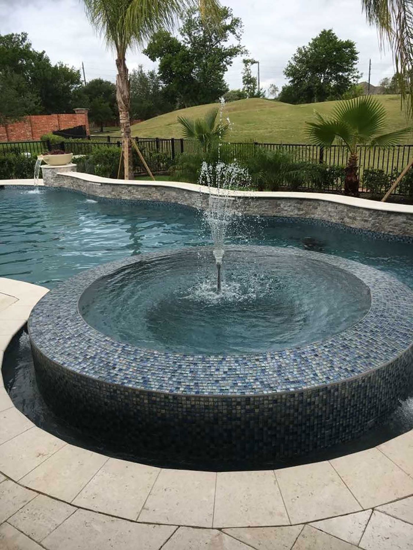 There is a fountain in the middle of the pool.