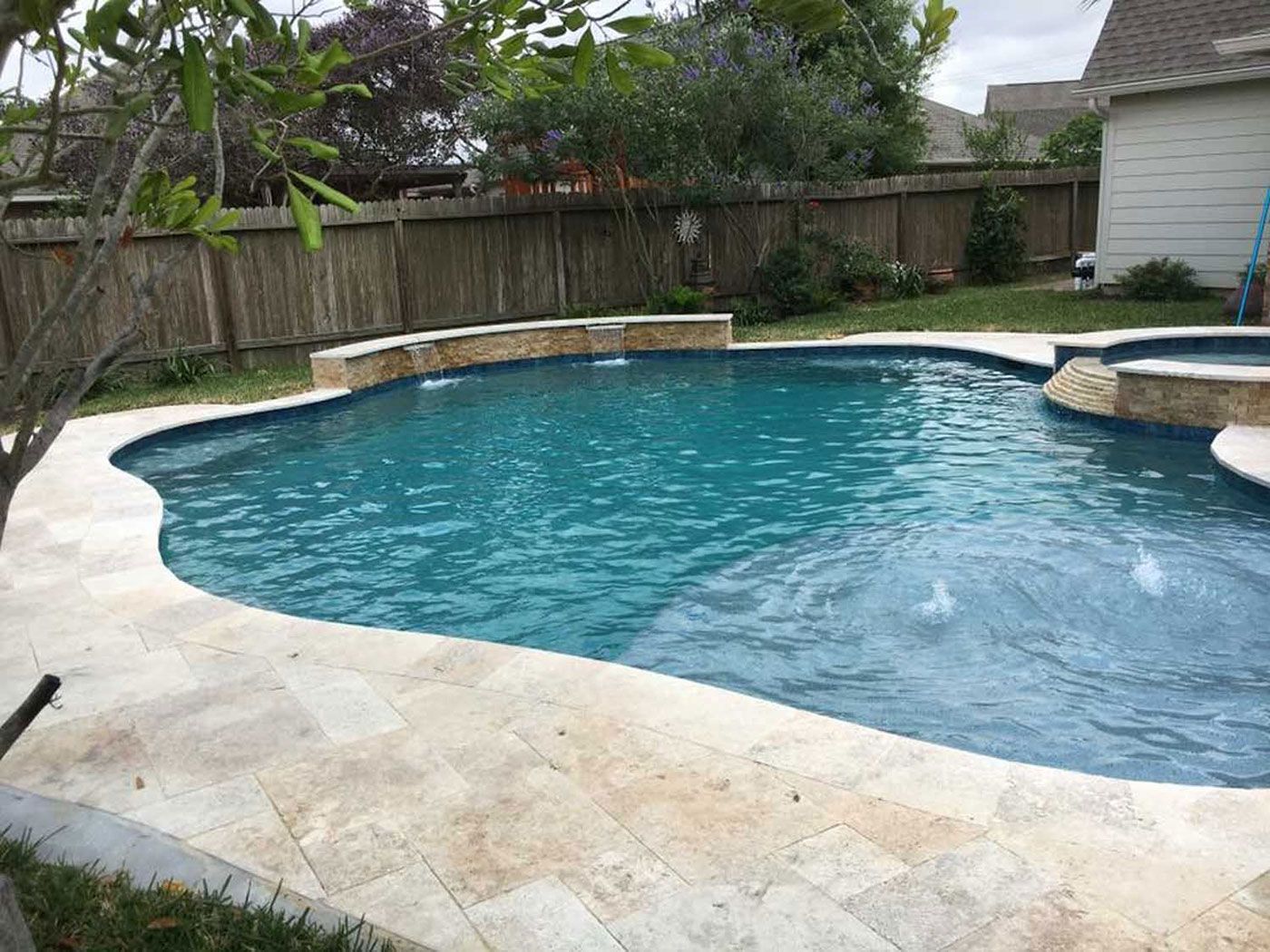 There is a large swimming pool in the backyard of a house.