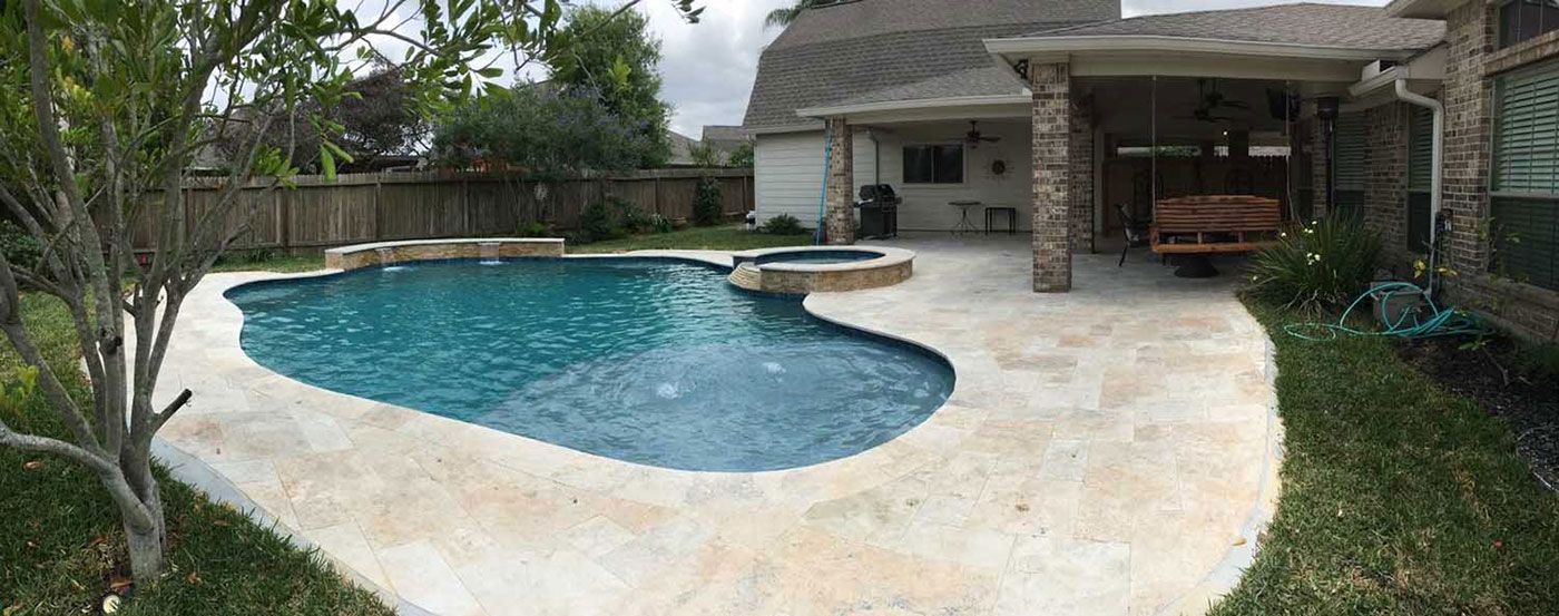 There is a large swimming pool in the backyard of a house.
