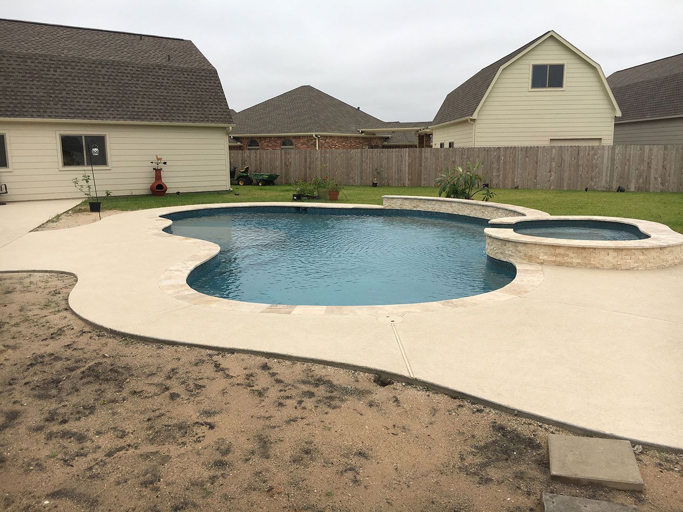 A large swimming pool is in the backyard of a house.