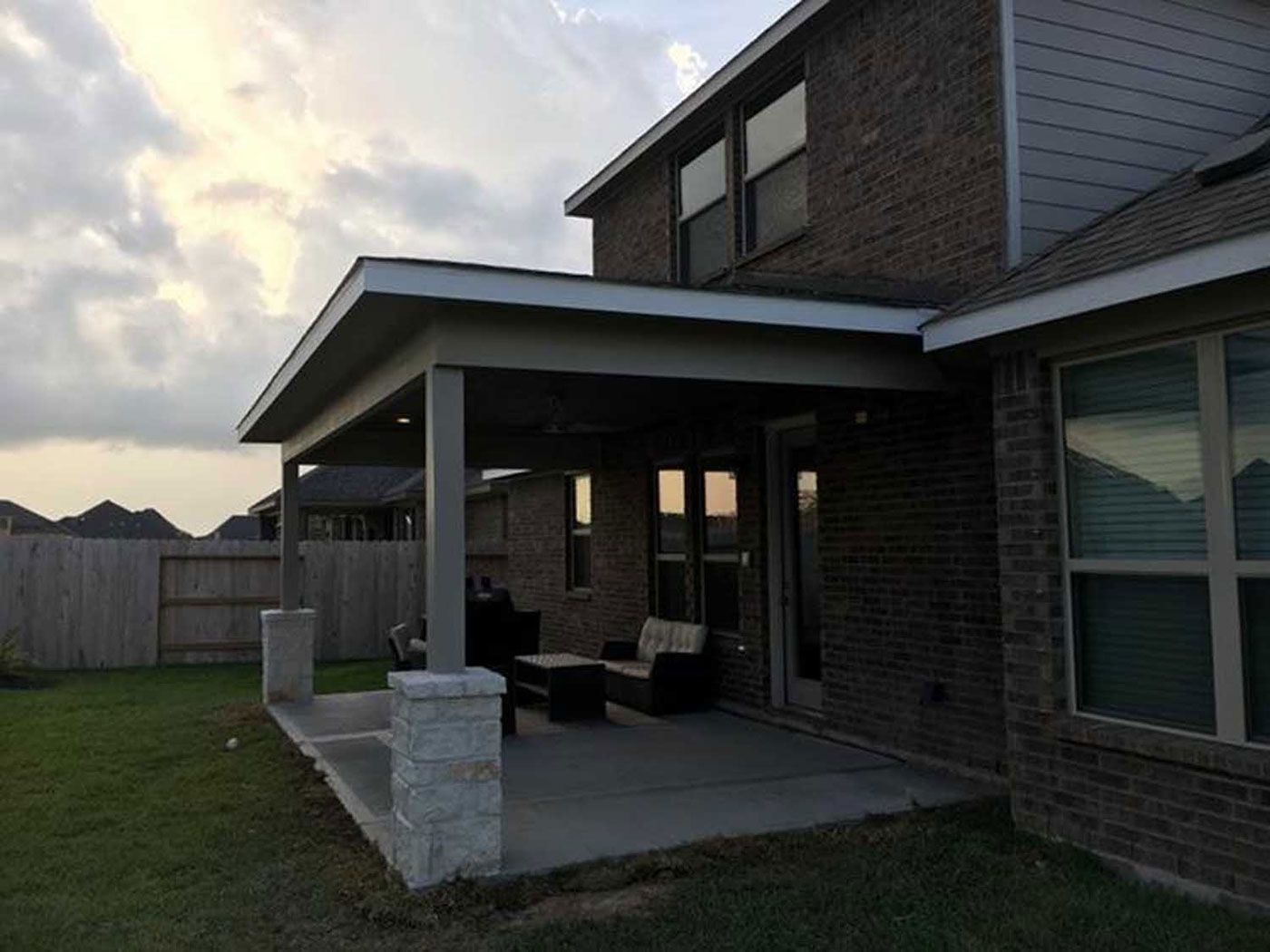 A brick house with a covered patio in the backyard