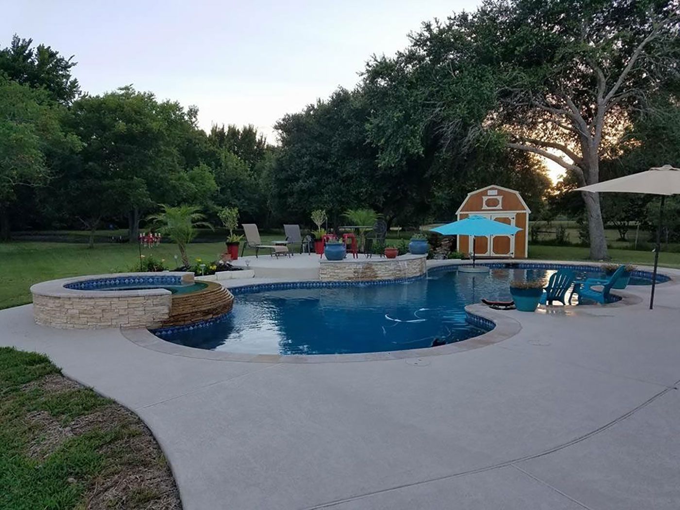 A large swimming pool in a backyard with a barn in the background.