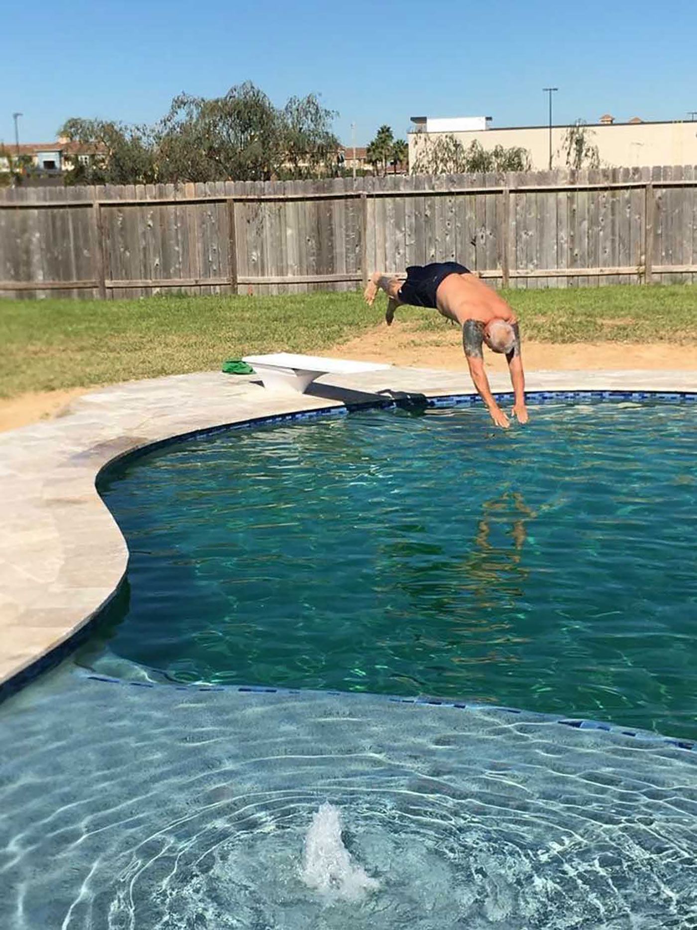 A man is doing a handstand into a swimming pool.