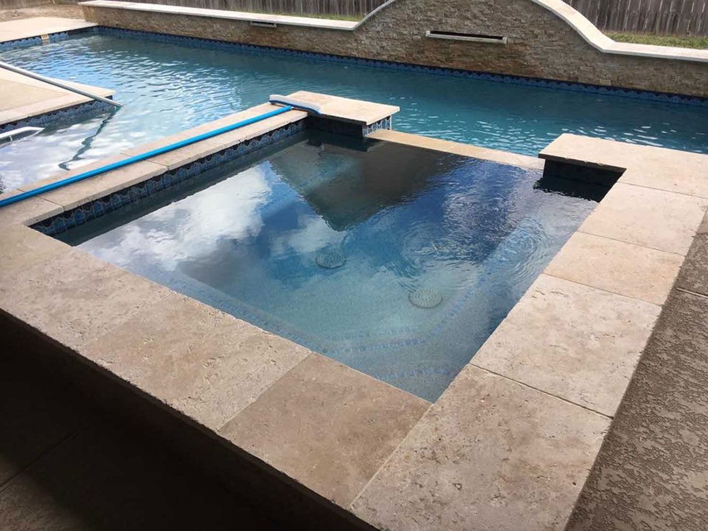 A large swimming pool with a hot tub in the middle of it.