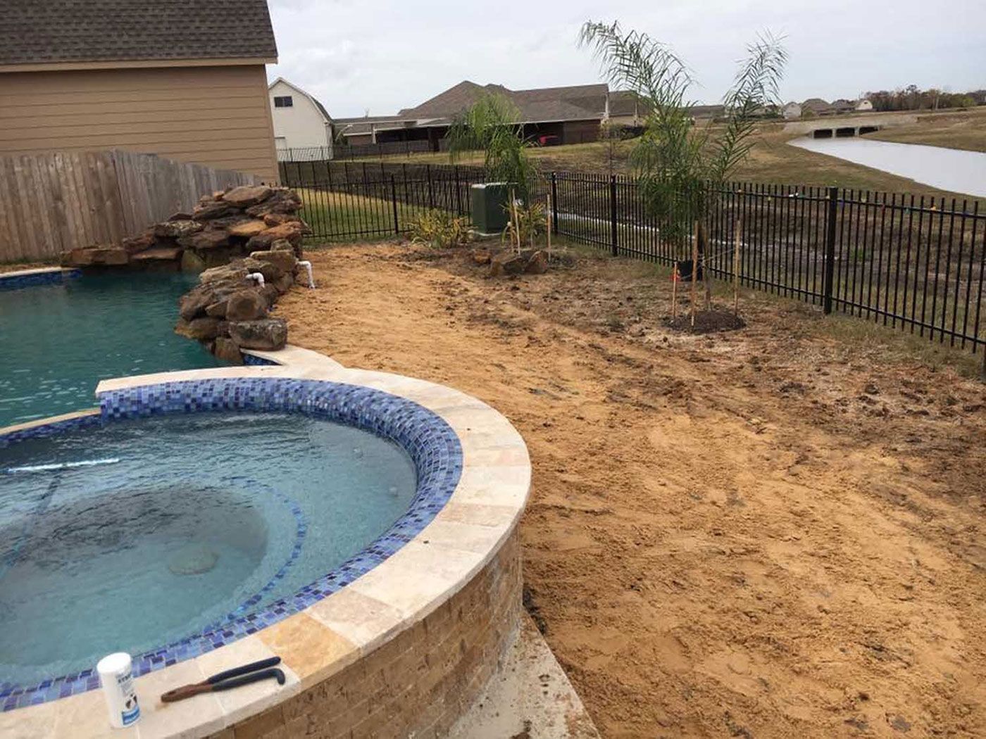 A hot tub is sitting next to a swimming pool in a backyard.