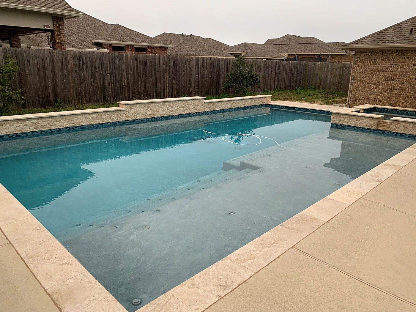 A large swimming pool with a wooden fence in the background
