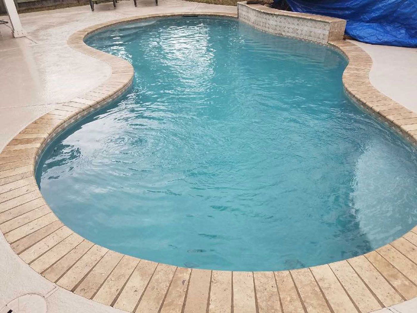 A large swimming pool filled with blue water and a wooden deck.