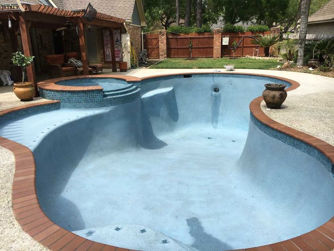 A large swimming pool with a hot tub in the backyard of a house.