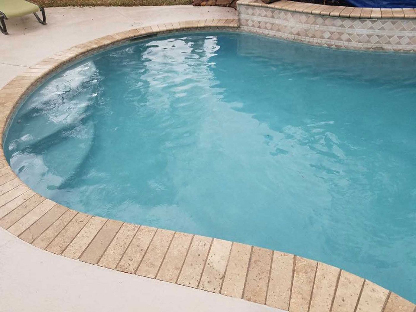 A large swimming pool filled with blue water and a wooden deck.