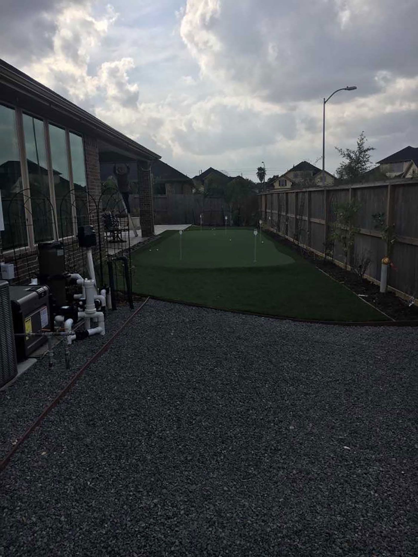 There is a putting green in the backyard of a house.