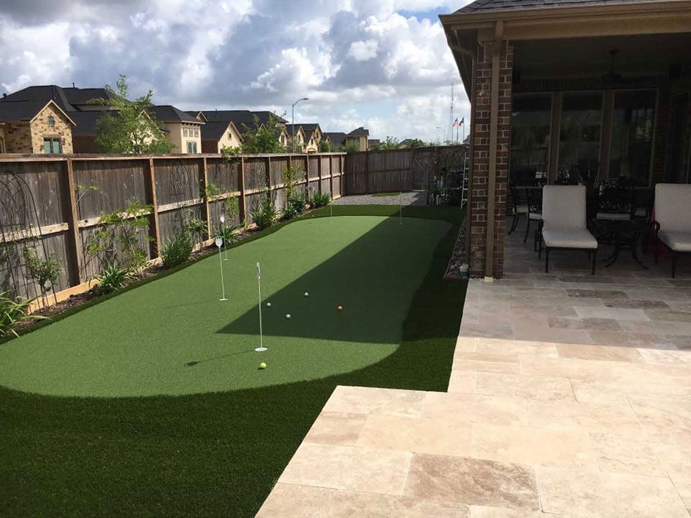 There is a putting green in the backyard of a house.