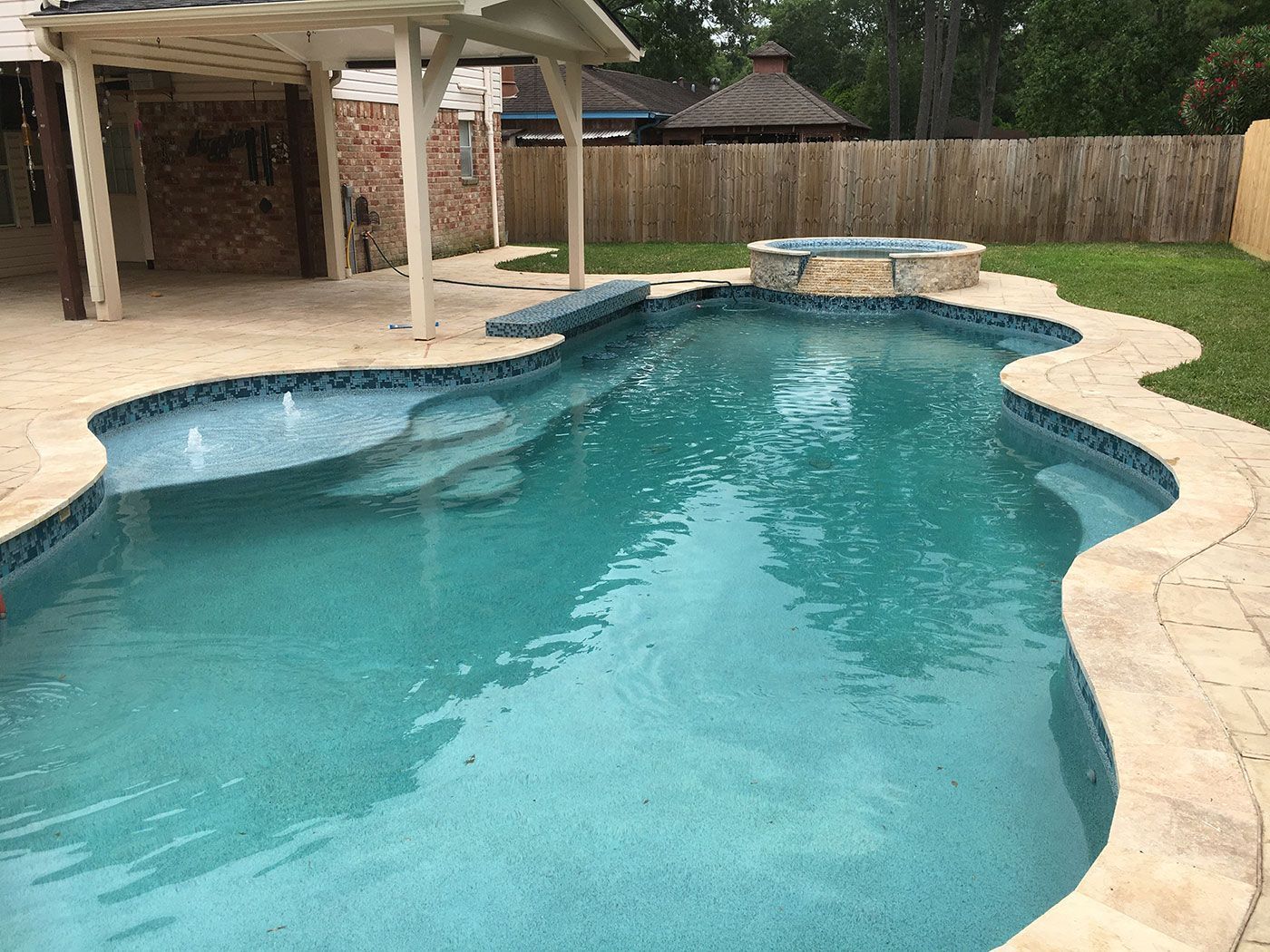 A large swimming pool with a hot tub in the backyard.