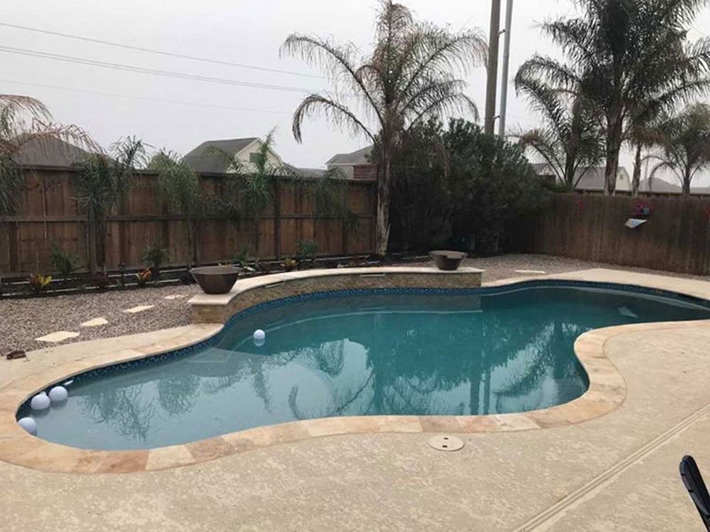 A large swimming pool in a backyard with palm trees in the background.