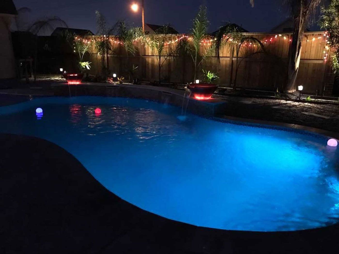 A swimming pool is lit up at night with blue lights