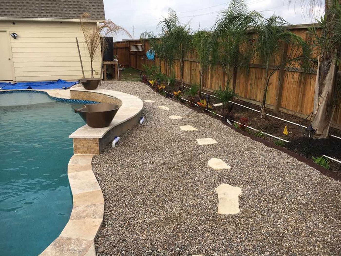 There is a swimming pool in the backyard with a walkway leading to it.