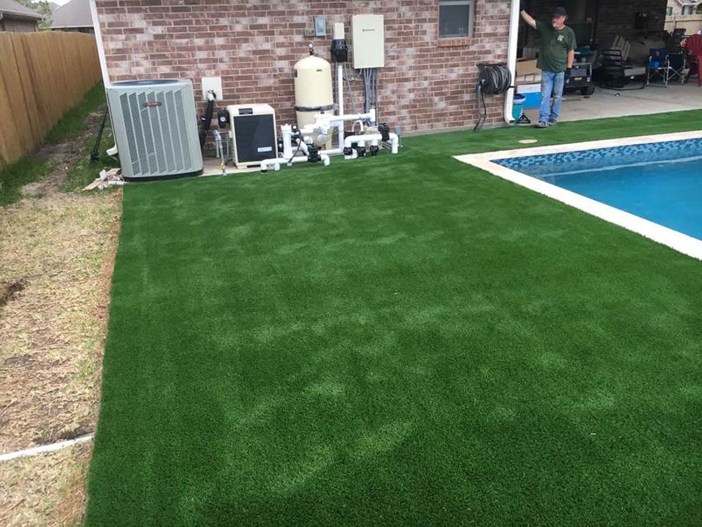 A man is standing next to a swimming pool in a backyard.