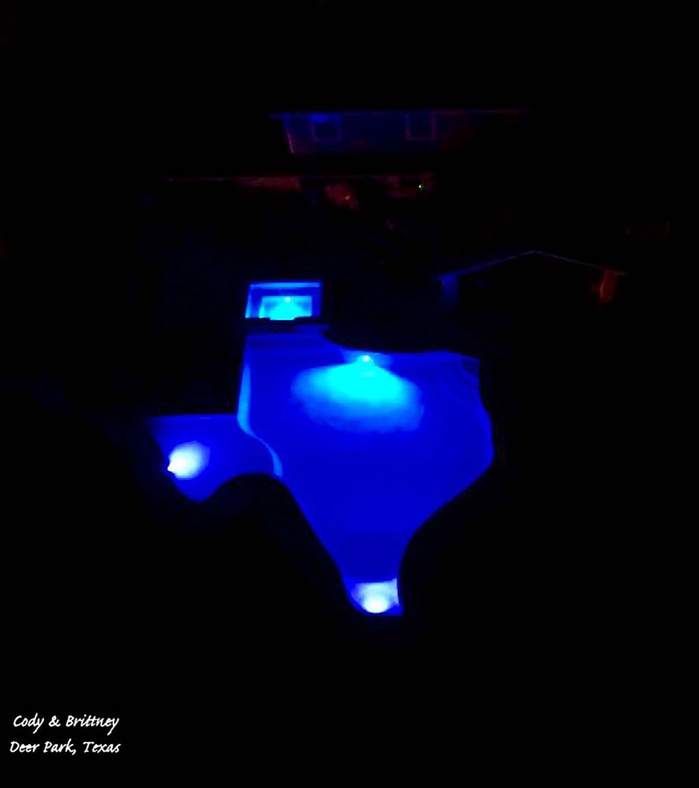 A person is sitting in a dark room with blue lights on the floor.