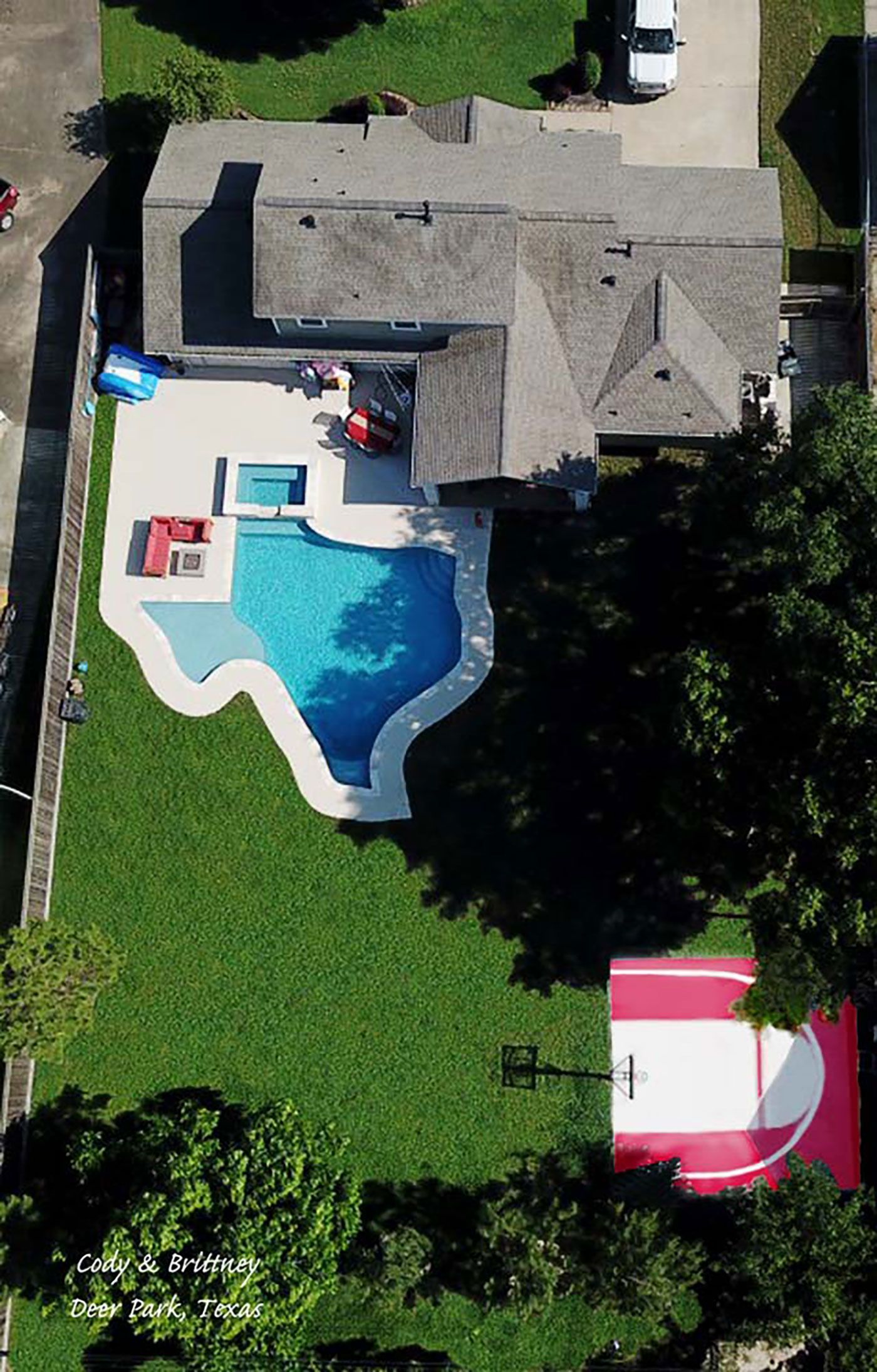 An aerial view of a house with a pool and a basketball court.