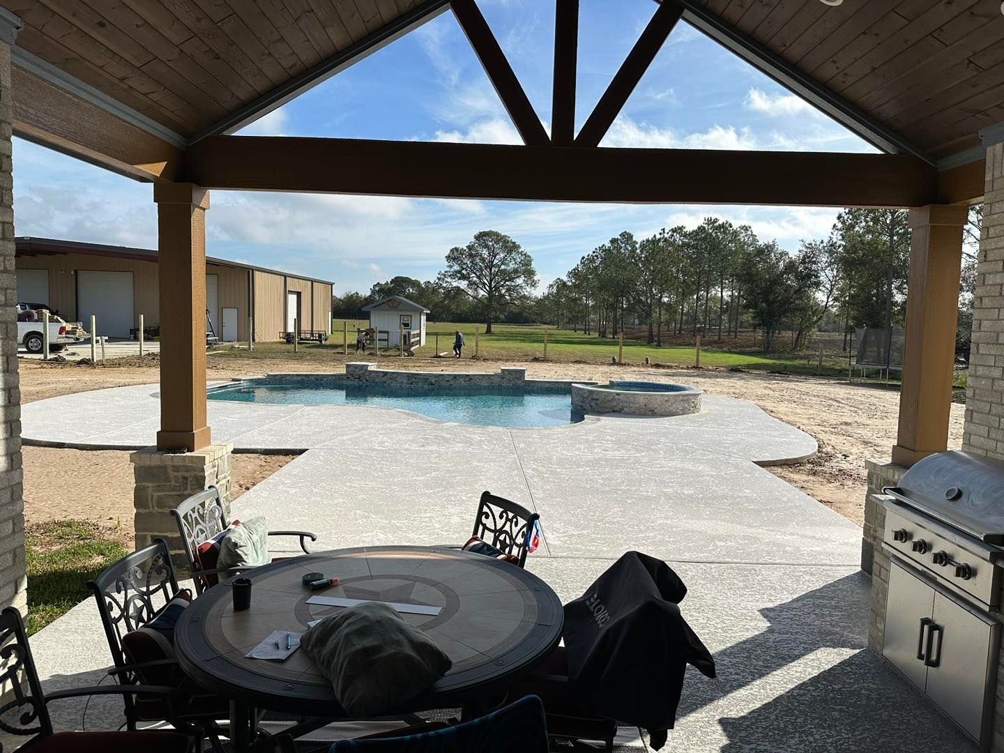 A patio with a table and chairs and a swimming pool in the background