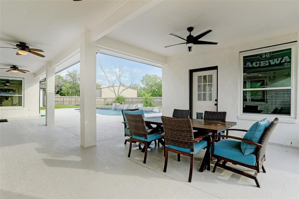 A patio with a table and chairs and a ceiling fan.