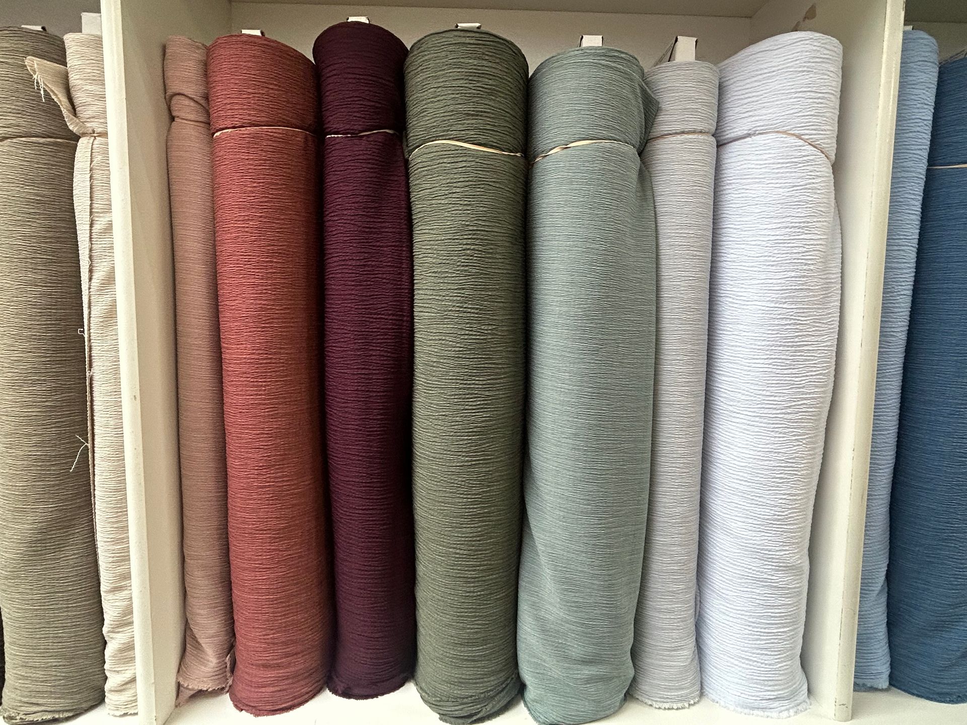 Shelves filled with various fabric rolls in a store; diverse colors and patterns.