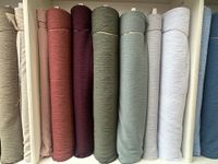 Shelves filled with various fabric rolls in a store; diverse colors and patterns.