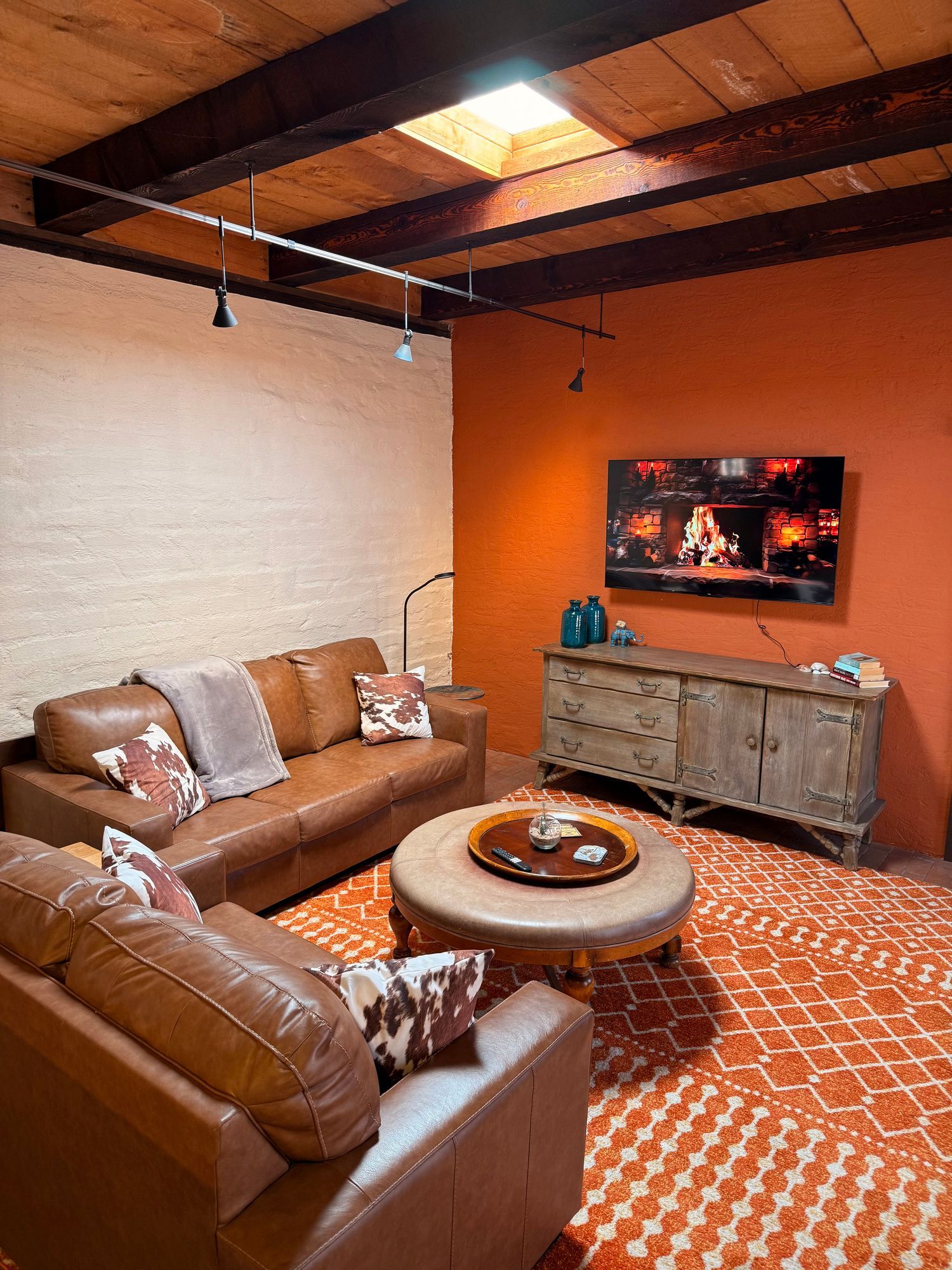 Cozy living room with brown leather sofa, orange rug, and terracotta-colored accent wall.