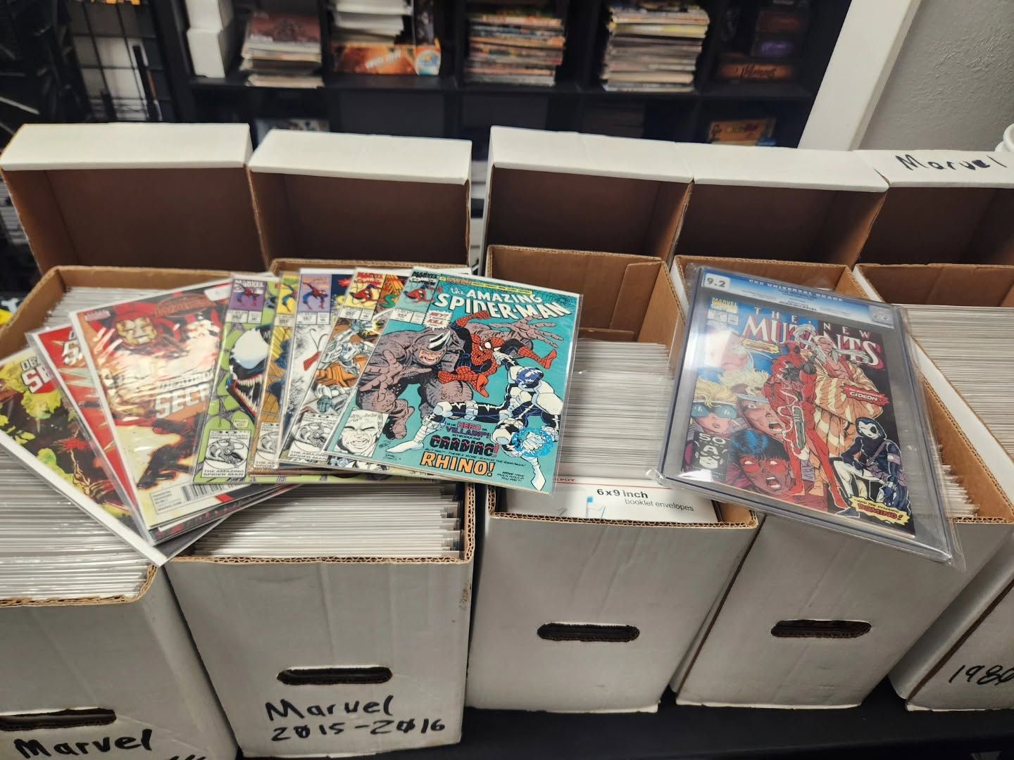 Boxes of comic books in a store, with colorful Marvel issues stacked on top.