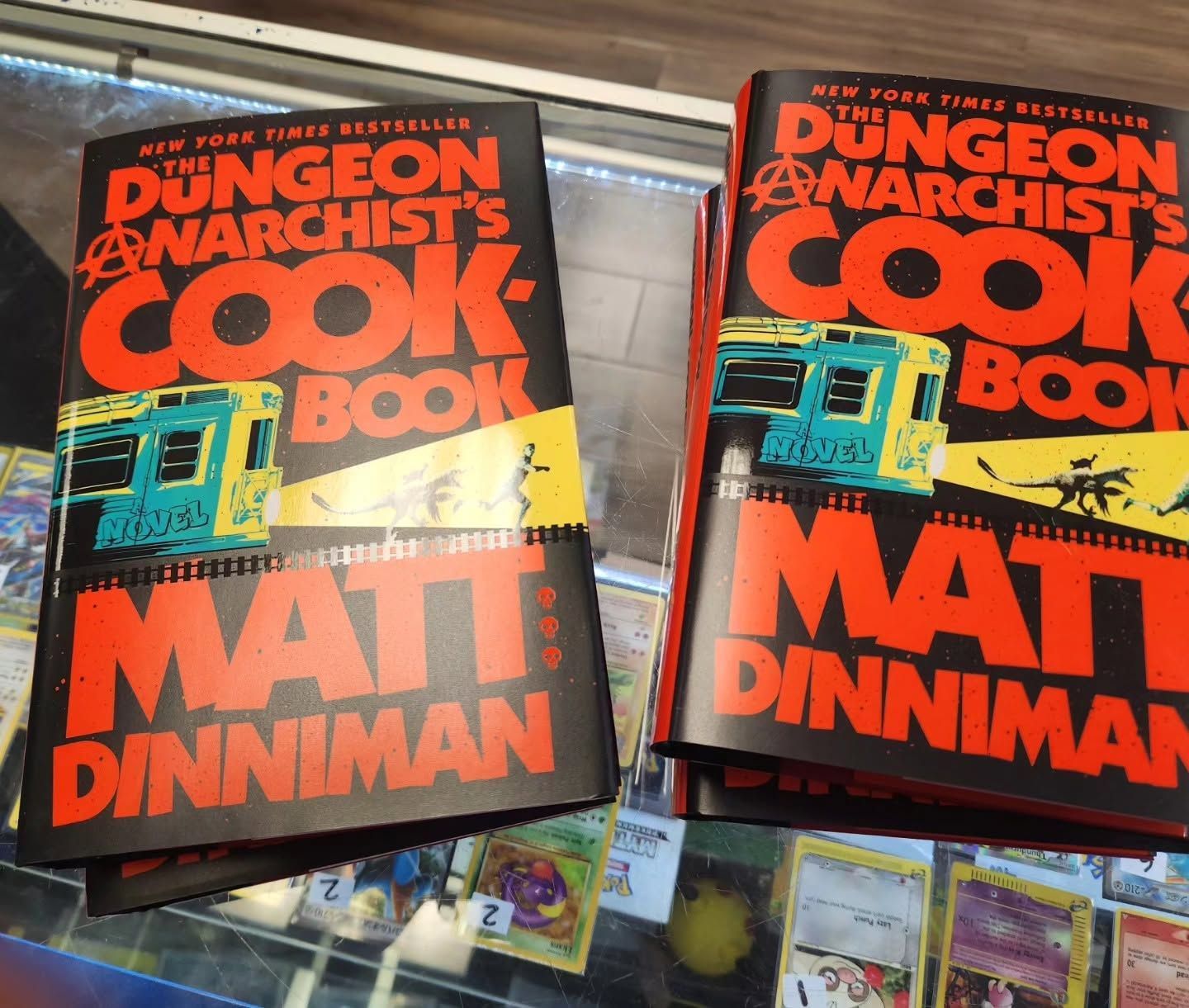 Two copies of Matt Dinniman’s “Dungeon Crawler Carl” cookbook on a store shelf.