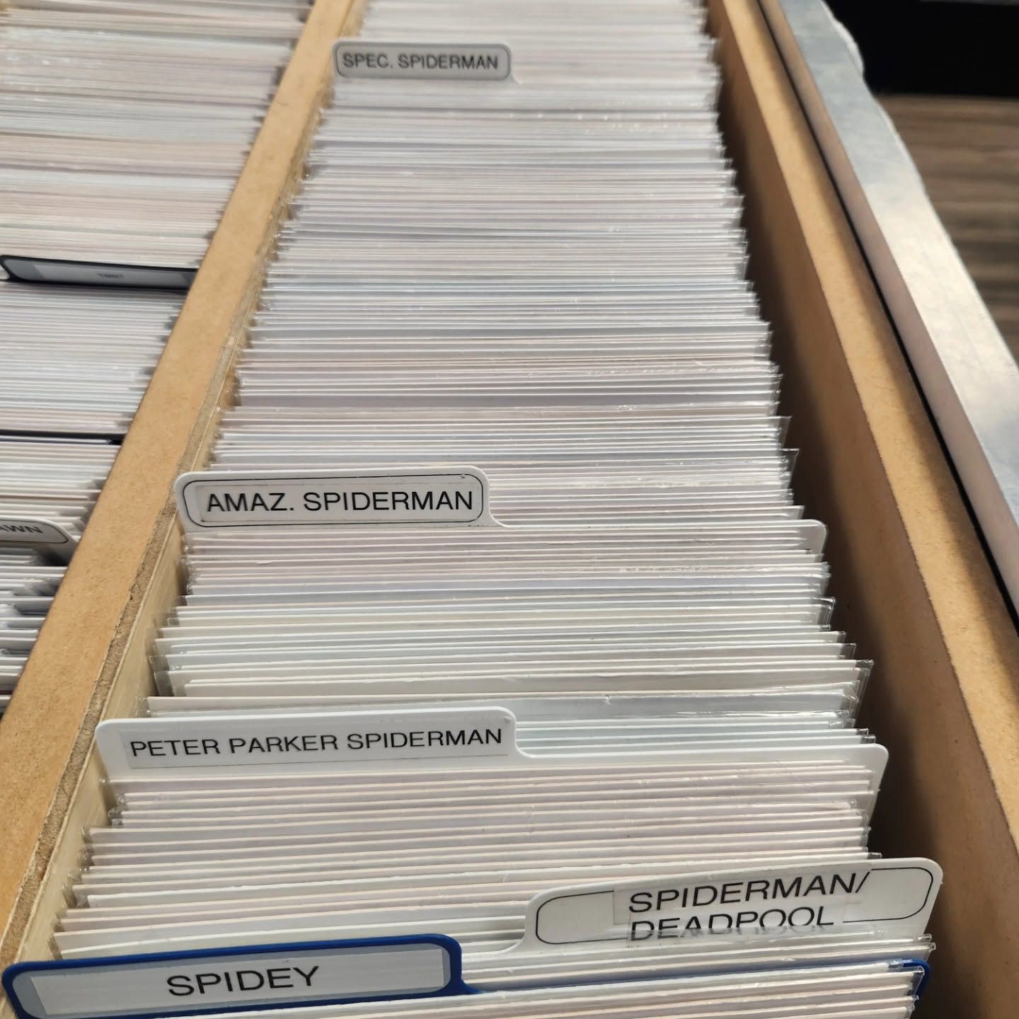 Drawer of alphabetized comic book dividers in a wooden file box, labeled Spider-Man and Spidey/Deadpool.